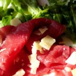Bresaola appesa a essiccare, con un focus su un taglio di carne di manzo.