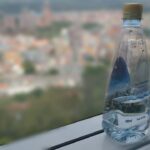Bottiglia d'acqua e bicchiere su un tavolo al mattino, simbolo di idratazione salutare.
