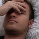 Immagine di una persona con una mano sulla testa, visibilmente afflitta da mal di testa al risveglio.